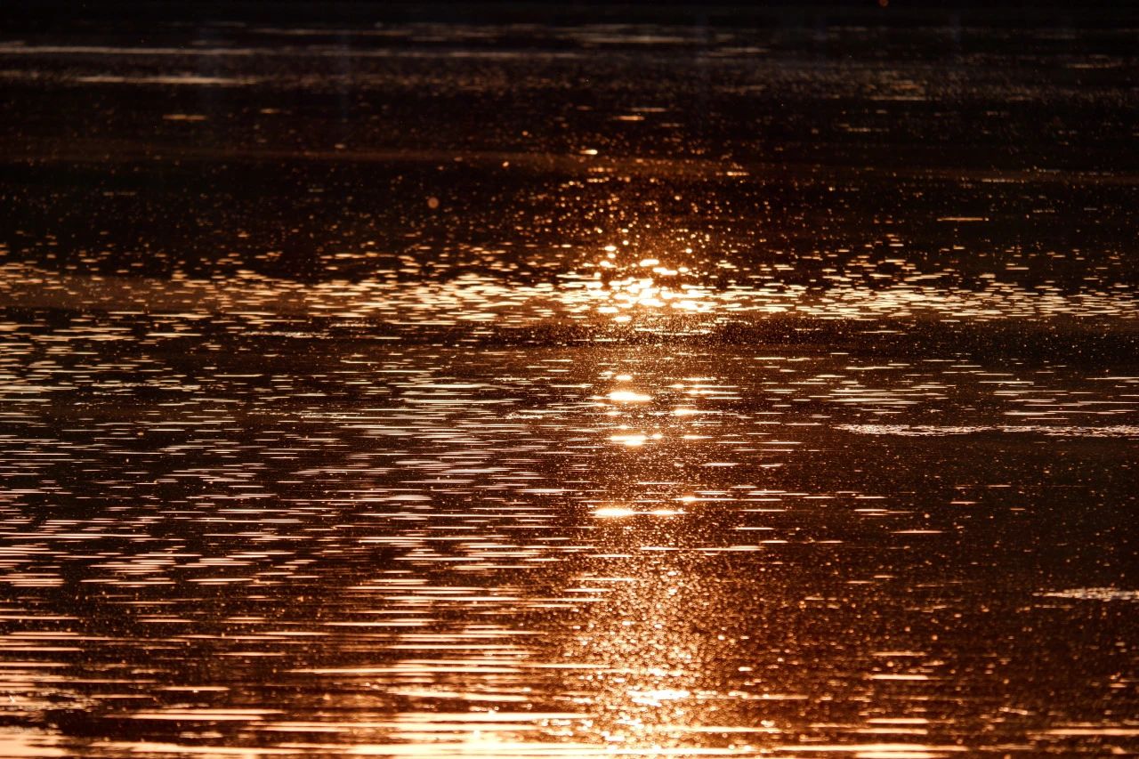 The setting sun reflects thousands of rays of rosy clouds by the lake.